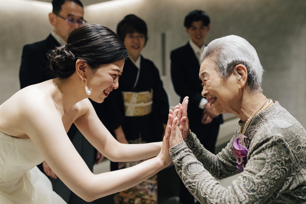 結婚式当日、花嫁と親族が手を取り合う様子