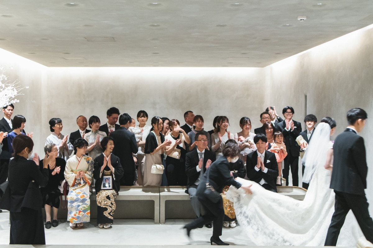 結婚式当日、拍手で迎える参列者と入場する新郎新婦の様子