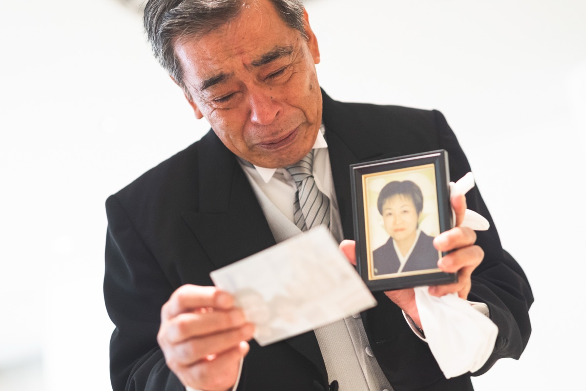 結婚式当日、写真立てを手に涙を拭う参列者の様子